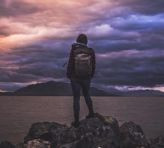 Foto eines Backpackers zur blauen Stunde, der in einen Himmel schaut